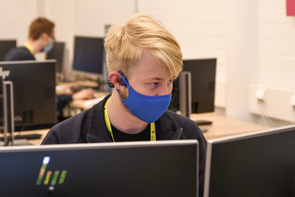 Me during the competition wearing a mask behind two computer monitors